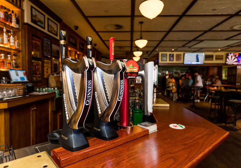 Beer taps and timber bar counter at The Galway Hooker Irish Pub in Scarborough, Western Australia, with the main bar and seating visible in the background.