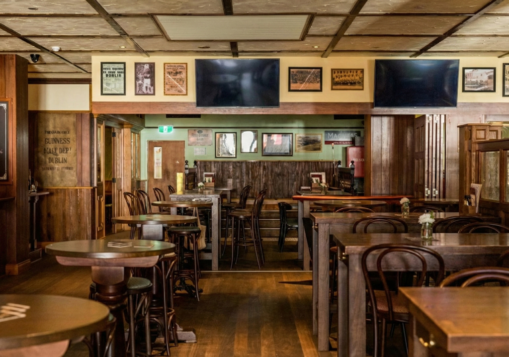 Main dining and seating area of The Galway Hooker Irish Pub in Scarborough, Western Australia, showing timber finishes, varied table heights, and layered seating zones.