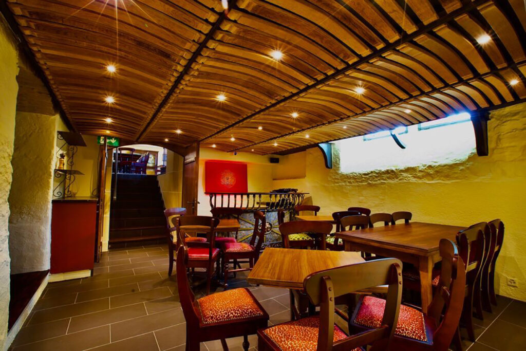 Lower-level dining area with vaulted timber ceiling at Red Piper gastropub in Vevey, Switzerland, showing communal tables and warm recessed lighting.