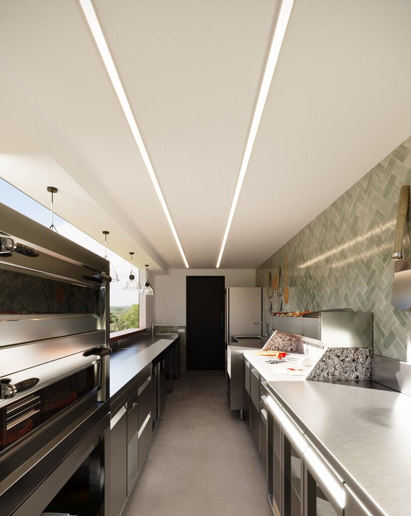 Interior of a shipping container pizza kiosk in Austria showing a linear commercial kitchen layout with pizza oven, stainless steel worktops, preparation counter, and overhead lighting.